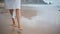 Woman legs leaving footprints at ocean shore closeup. Carefree girl walking sand