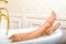 Woman legs lying in white bathtub