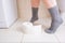 Woman legs in socks on a toilet with a roll of toilet paper in hands, digestive problems and defecation disorder concept