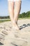 Woman legs step on warm sandy beach