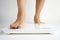 Woman legs stepping on floor scales, close-up