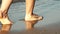 Woman legs walking on golden sand beach. 4K.