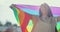 Woman lesbian holds a LGBT gender identity flag on a background. Smiled young woman spinning around with lgbt flag on