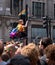Woman with LGBT rainbow climbs up the traffic light pole at Oxford Circus to get a better view of the Gay Pride Parade.