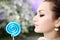 Woman licking a blue shiny lollipop close up against nature background