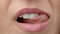Woman licks her lips close up. Gentle female tongue licks beautiful white teeth.
