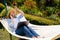 Woman lies in hammock, answers phone call