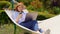 Woman lies in hammock and working on computer