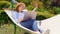 Woman lies in hammock and working on computer