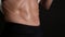 Woman lifts a white T-shirt with hands and shows muscular sweaty belly, close-up against a darkness background. Concept