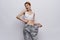 Woman on a light background holding pants, losing weight, diet, sports, fitness, success, progress