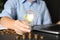 Woman with light bulb and coins at wooden table, closeup. Power saving