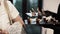 Woman in light clothes tries snacks on tray offered by waiter in black uniform.