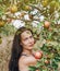 Woman in a light summer dress framed by twigs of apple trees in