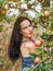 Woman in a light summer dress framed by twigs of apple trees in