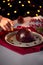 Woman Lighting Brandy Soaked Christmas Pudding On Table Set For Festive Christmas Meal