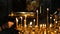 Woman lights a wax candle in a censer in an Orthodox Catholic ancient temple