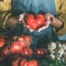 Woman in linen apron holding ripe heirloom tomato, square crop