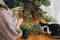 Woman in linen dress arranging flowers and two cats playing and smelling wildflowers on wooden table