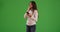 Woman listening to music on cell phone and dancing on green screen