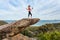 Woman listening to music or a playlist high up on a balancing rock on mountain edge.