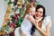 A woman with a little girl in beautiful white dresses in a bright studio decorated with flowers. Mother and daughter play, hug,