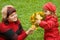 Woman and little girl collect maple leafs In park