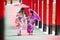 Woman and little girl in kimono holding umbrella walking into at the shrine red gate, in Japanese garden