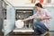 Woman Loading Dishwasher In Kitchen