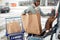 Woman loading food from shopping cart to car trunk