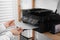 Woman loading paper into printer on shelf indoors, closeup