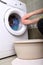 Woman loading the washing machine in bathroom