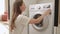 Woman loads dirty colored clothes into a washing machine. A woman puts up a washing program on a washing machine