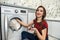 Woman  loads the laundry clothes into washing machine