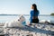 Woman with Locs Sitting on the Beach of City Lake with Her Best Friend, Snow-White Dog Breed Japanese Spitz