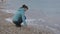 Woman at lonely cold beach. Attractive caucasian woman playing with stones near the water on the beach.