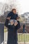 woman with a long black coat holding a cute African American curled little boy who is smiling upwards vertical outside