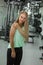 A woman with long blonde hair feels severe shoulder pain during a workout in the gym. People, fitness and healthcare concept. It