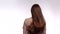 Woman with long brown hair stands whaite backround and shakes head slightly, back view . Woman shakes head slightly with
