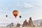 Woman in a long dress on background of balloons in Cappadocia. Girl with flowers hands stands on a hill and looks