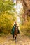 A woman in a long dress sits on a horse. Autumn forest, horse breeding