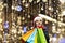 A woman with long hair and a Santa hat near the window of a city store with purchases in colorful, paper bags. New year`s shoppin