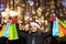 A woman with long hair and a Santa hat near the window of a city store with purchases in colorful, paper bags. New year`s shoppin