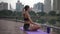 Woman with long hair tail relaxing on the fitness carpet after her yoga in city park around megapolis