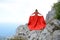 Woman in long red dress on the edge of a cliff in the mountains. Peak of Ai-Petri mountain