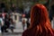 a woman with long red hair is looking at a sidewalk