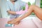 Woman with long tanned perfect legs and smooth skin having wax stripe depilation hair removal procedure on legs in beauty salon.