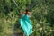 Woman in long turquoise dress swinging in the jungle, Bali