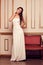 Woman in long white evening wedding dress in antique interior. L