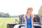 Woman looking away while sitting on convertible trunk against clear sky